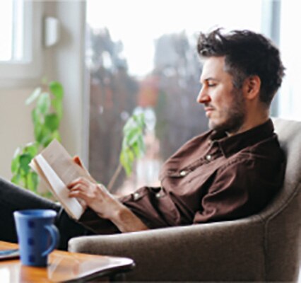 Man sitting in a chair, reading a book