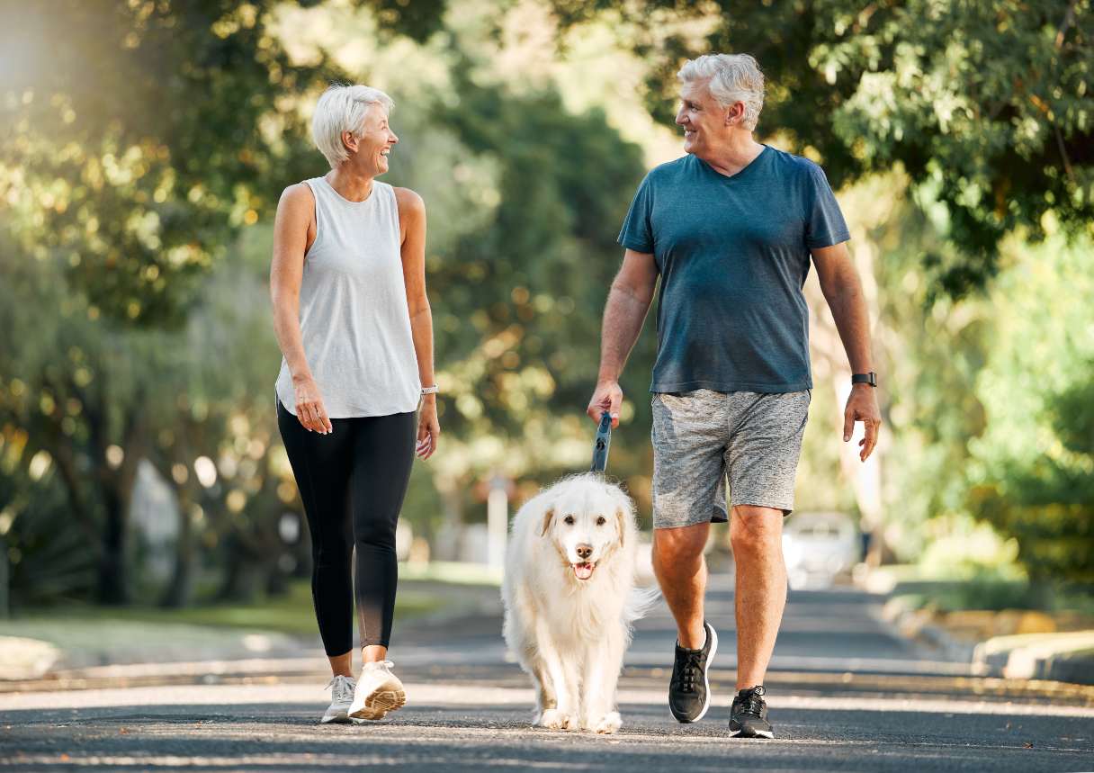 Man and woman walking dog outside