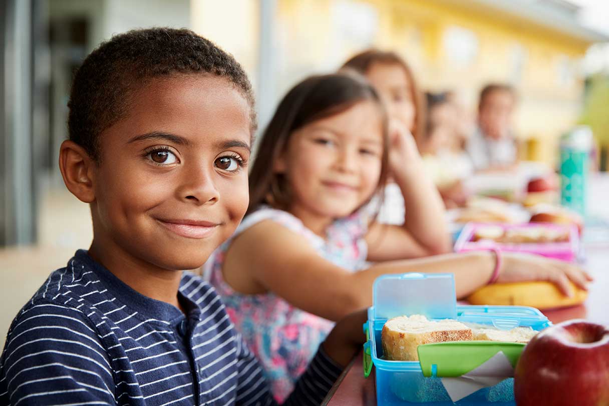 Group of children smiling and sitting at lunch table