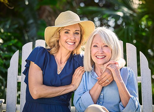 Two smiling women sitting on white bench