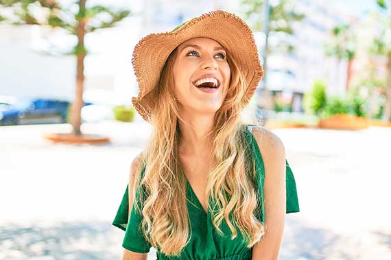 Woman in green dress and straw hat, smiling