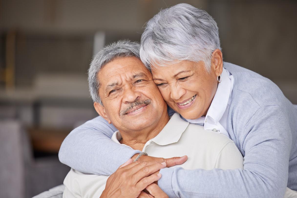 Senior woman with arms around senior man