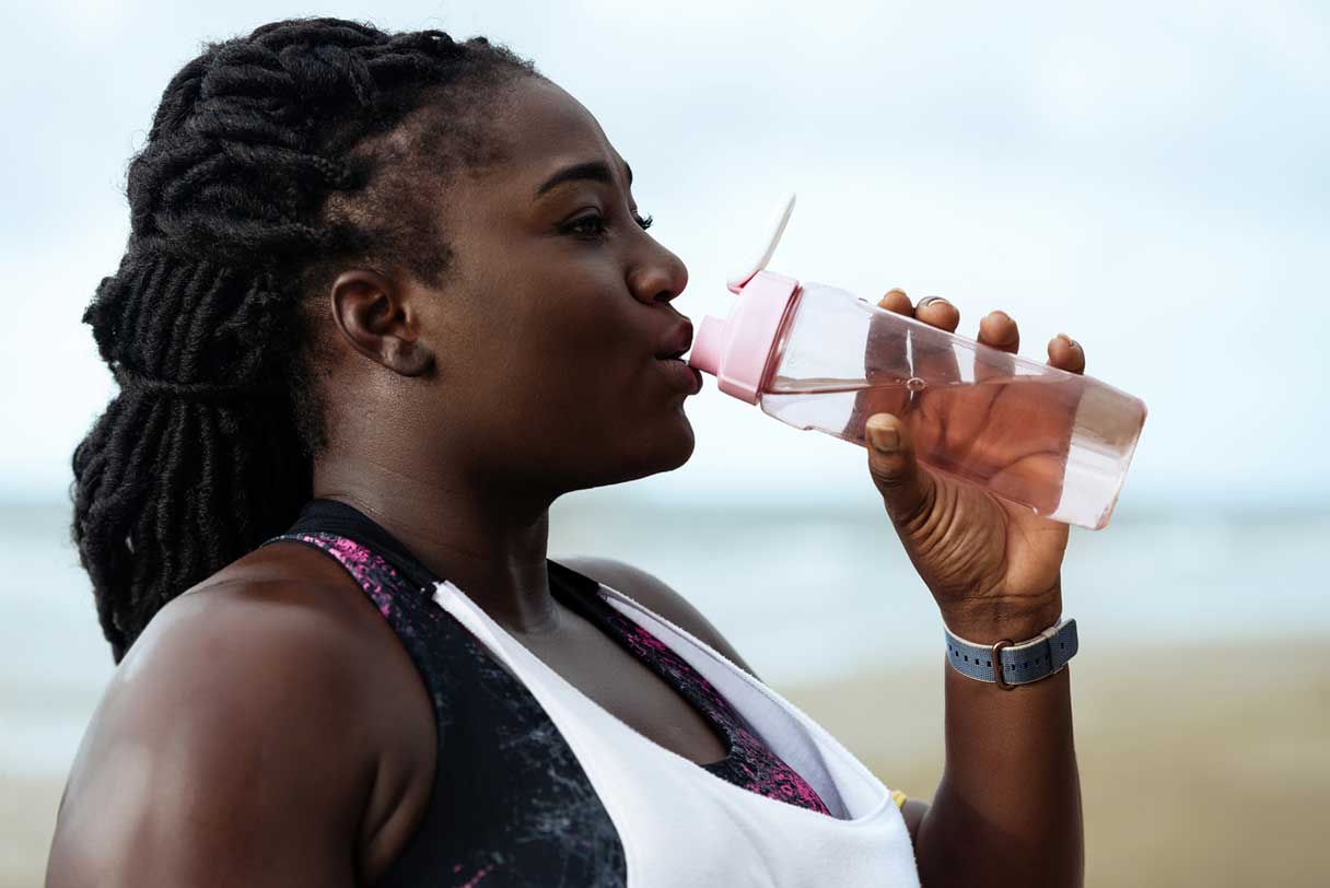 Woman standing outside, drinking from water bottle