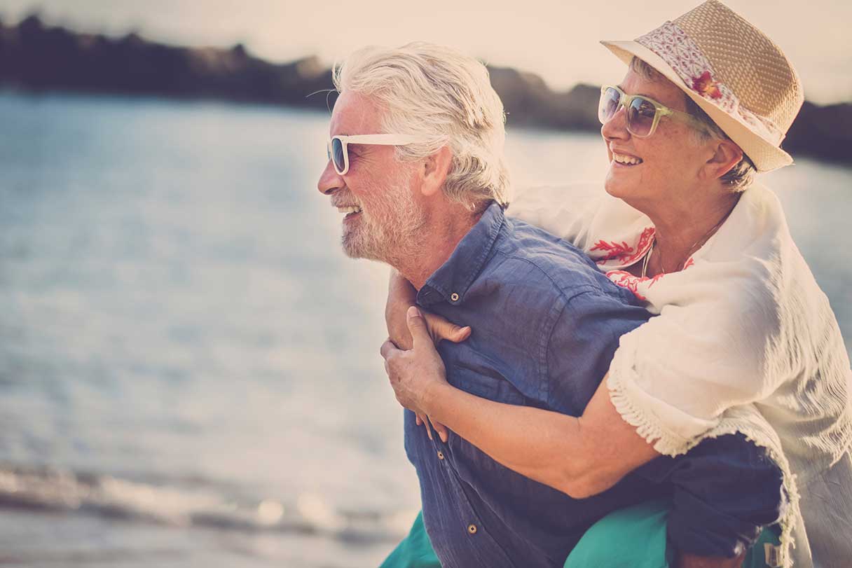 Senior man carrying senior woman on his back