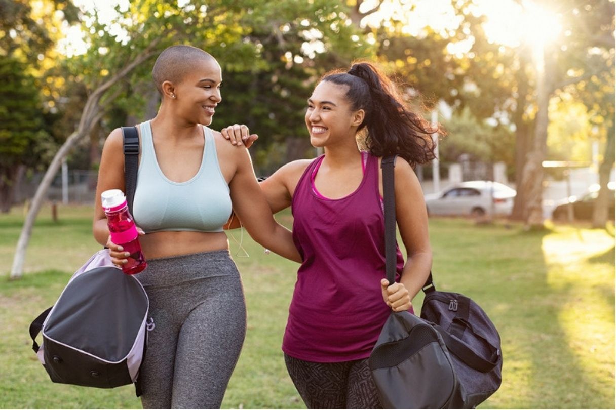 Two women in athletic wear, walking in a park