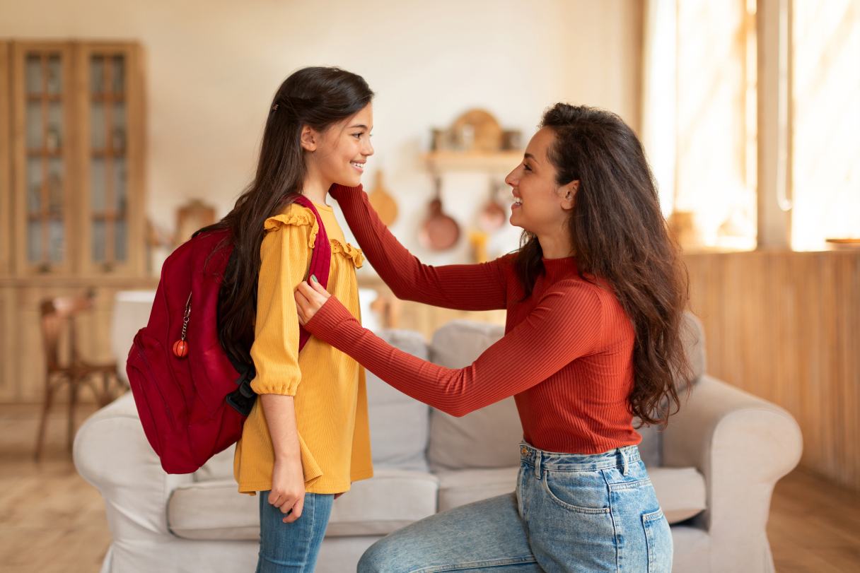 Woman placing a backpack on her daughter