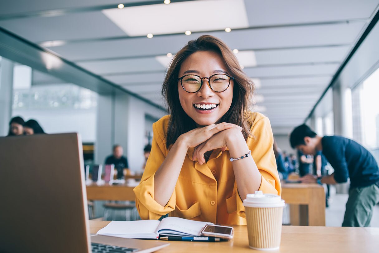 Woman smiling, sitting in an office in front of a laptop