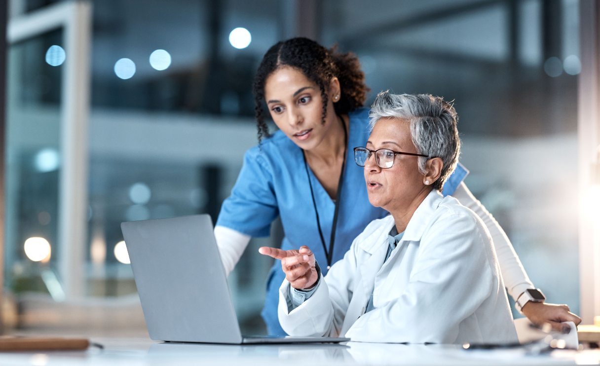 Two healthcare professionals looking at laptop screen