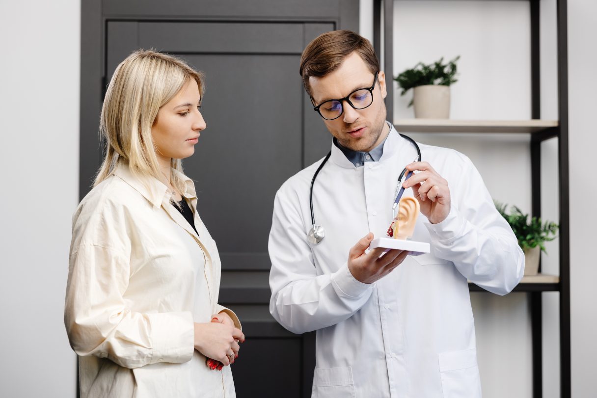 Hearing professional pointing to model of an ear