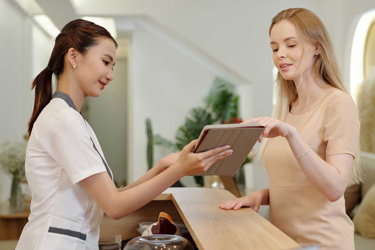Receptionist showing a woman a tablet device