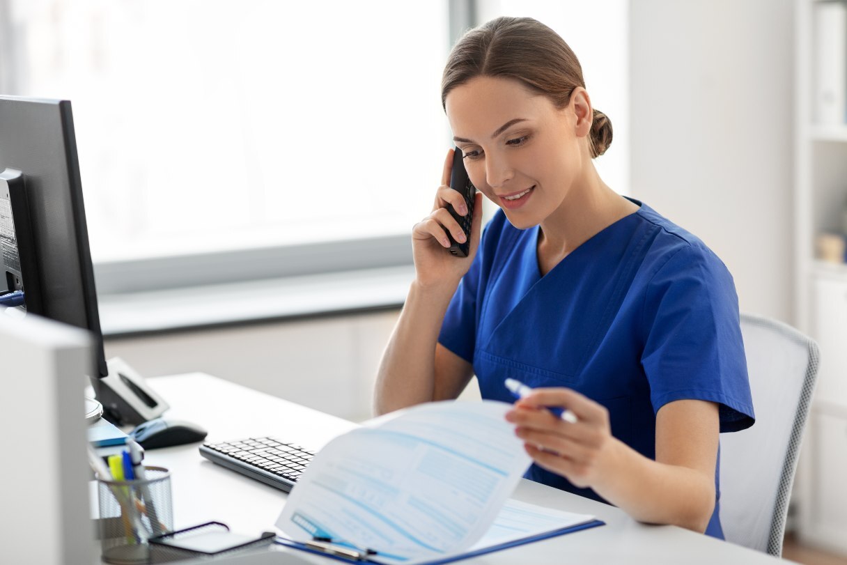 Receptionist on phone, looking at clipboard