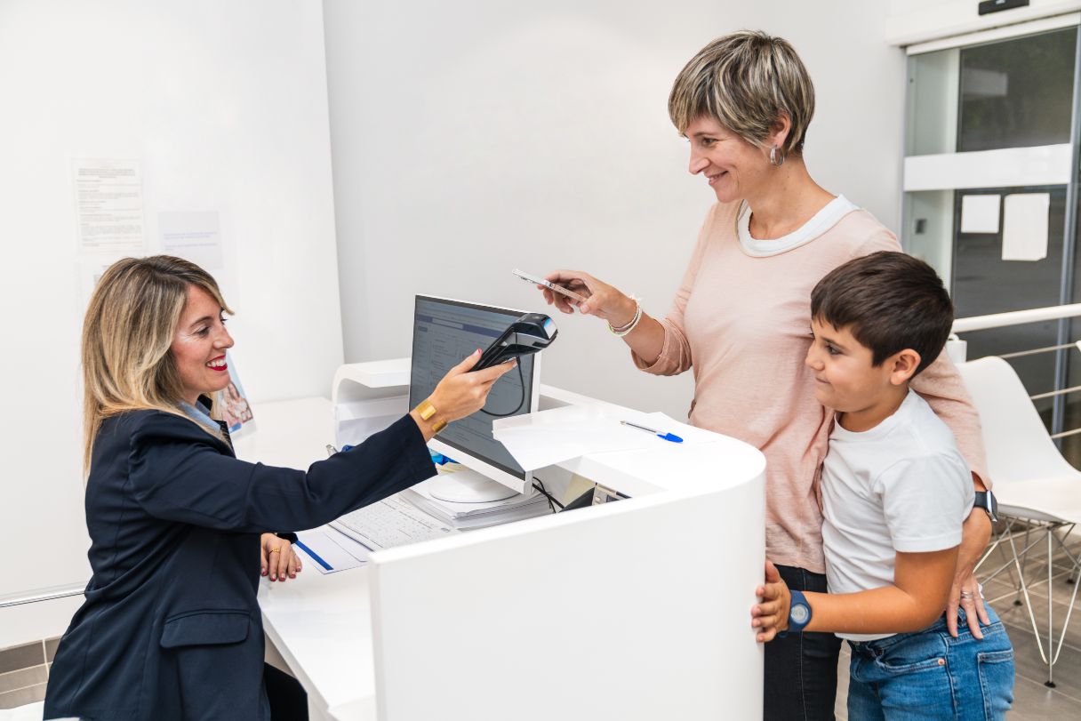 Woman with young boy paying at healthcare office with credit card