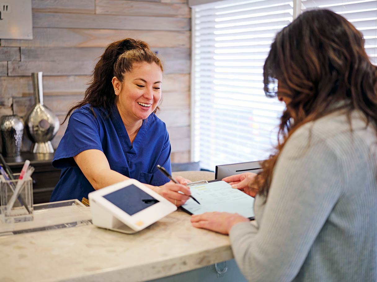Receptionist helping patient with paperwork on clipboard