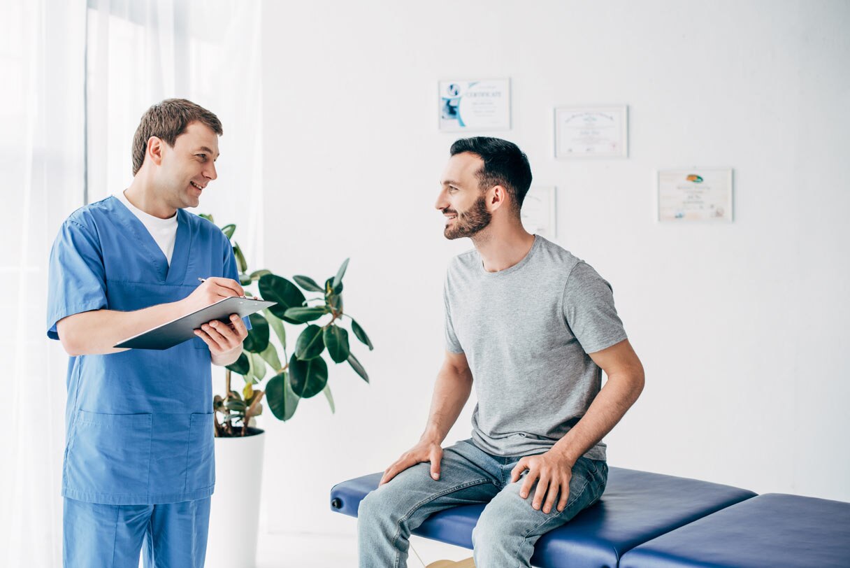 Chiropractor speaking to client sitting on adjustment table