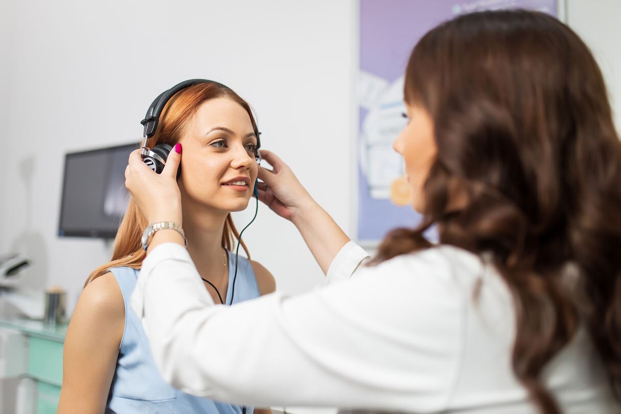 Doctor showing fitting headphones over woman's ear