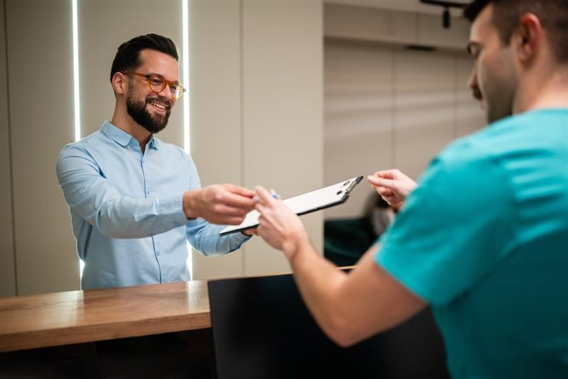 Receptionist passing a man a clipboard