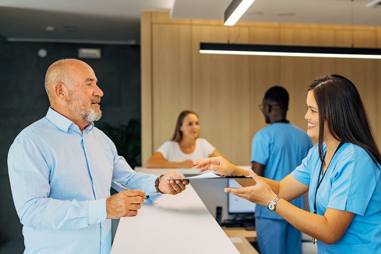 Man passing receptionist a clipboard