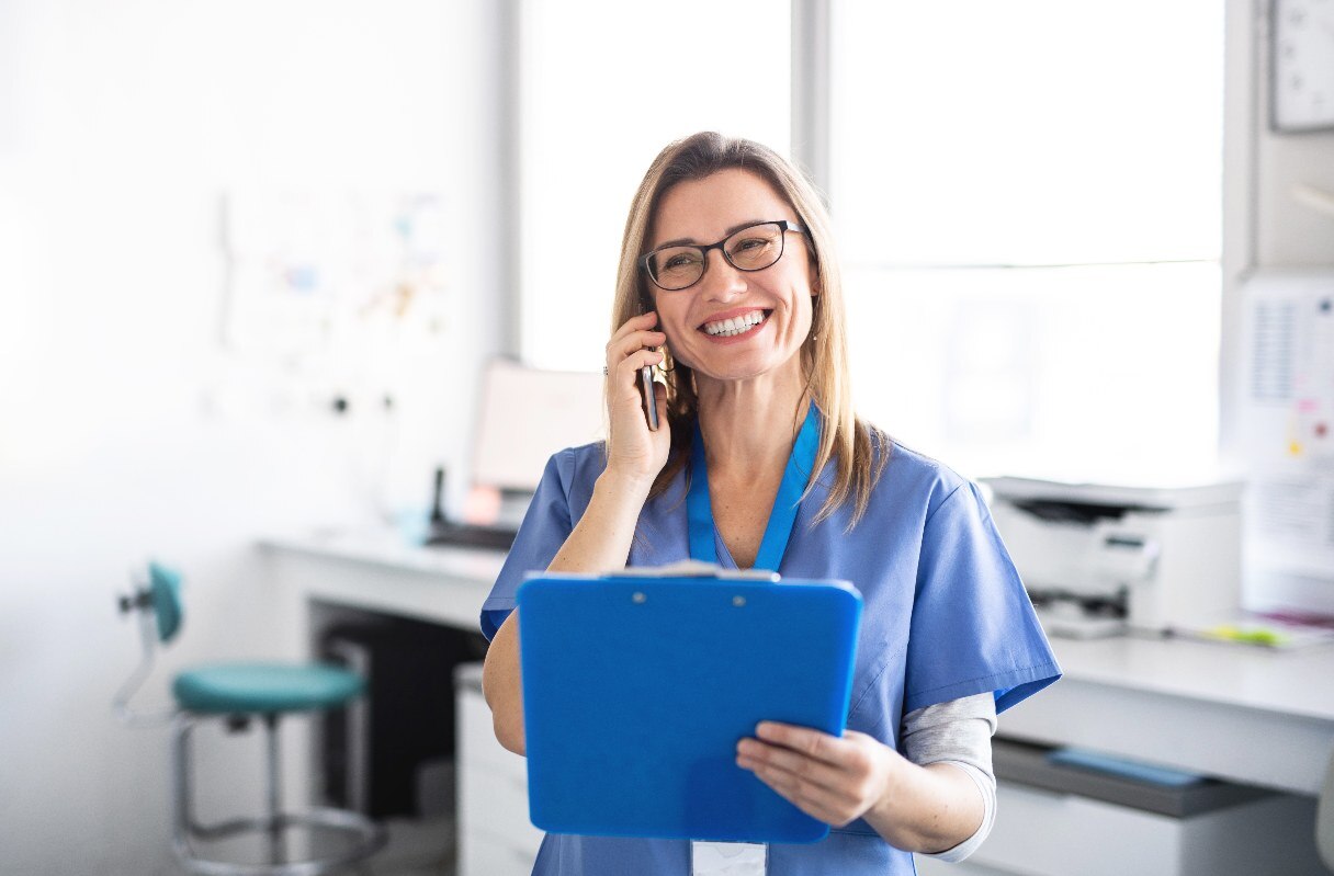 Dental receptionist on the phone, holding clipboard