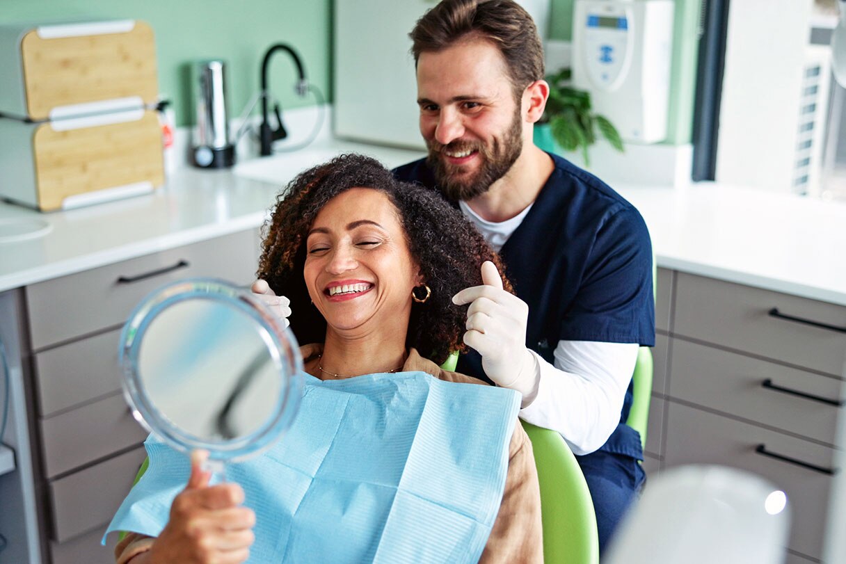 Dentist showing patient smile in a handheld mirror