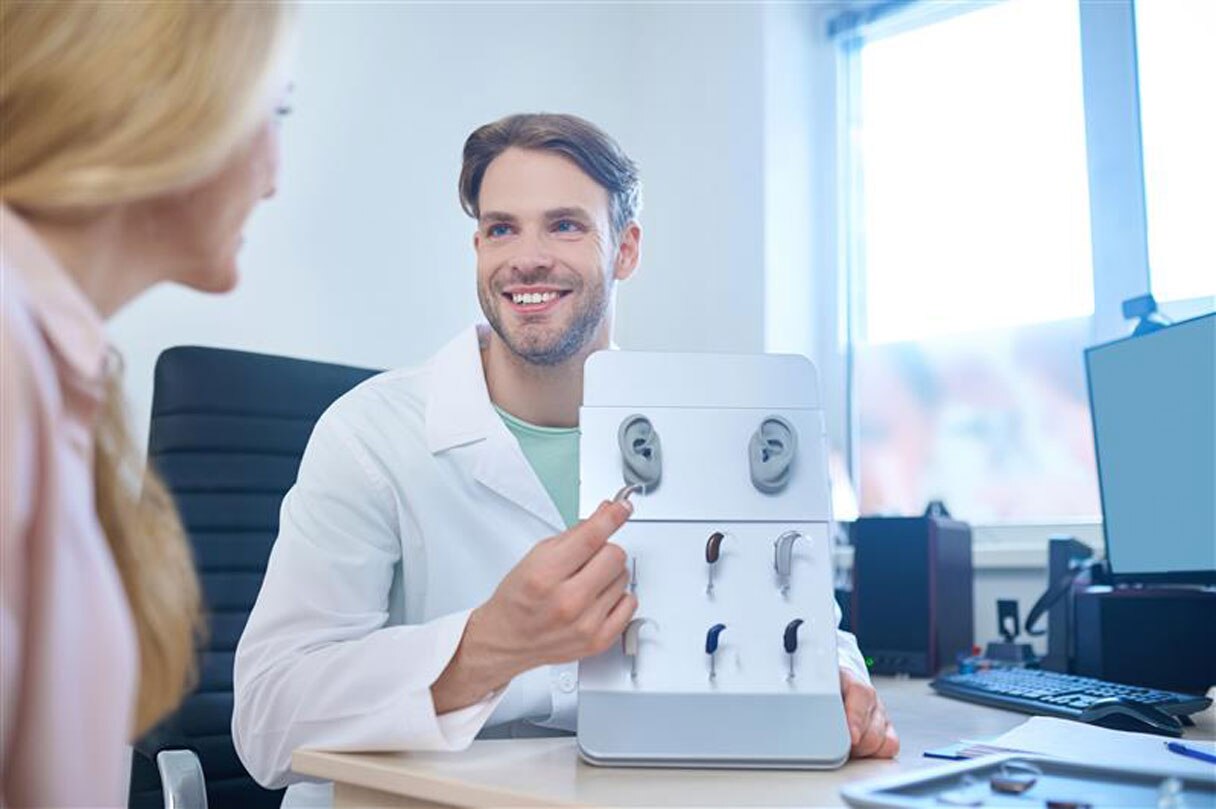 Doctor showing woman hearing device options