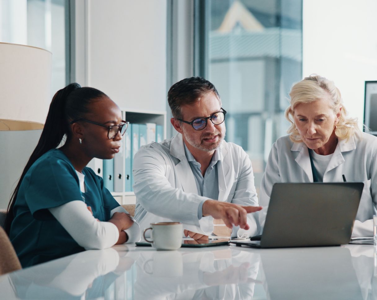 Three healthcare professionals working together on a laptop