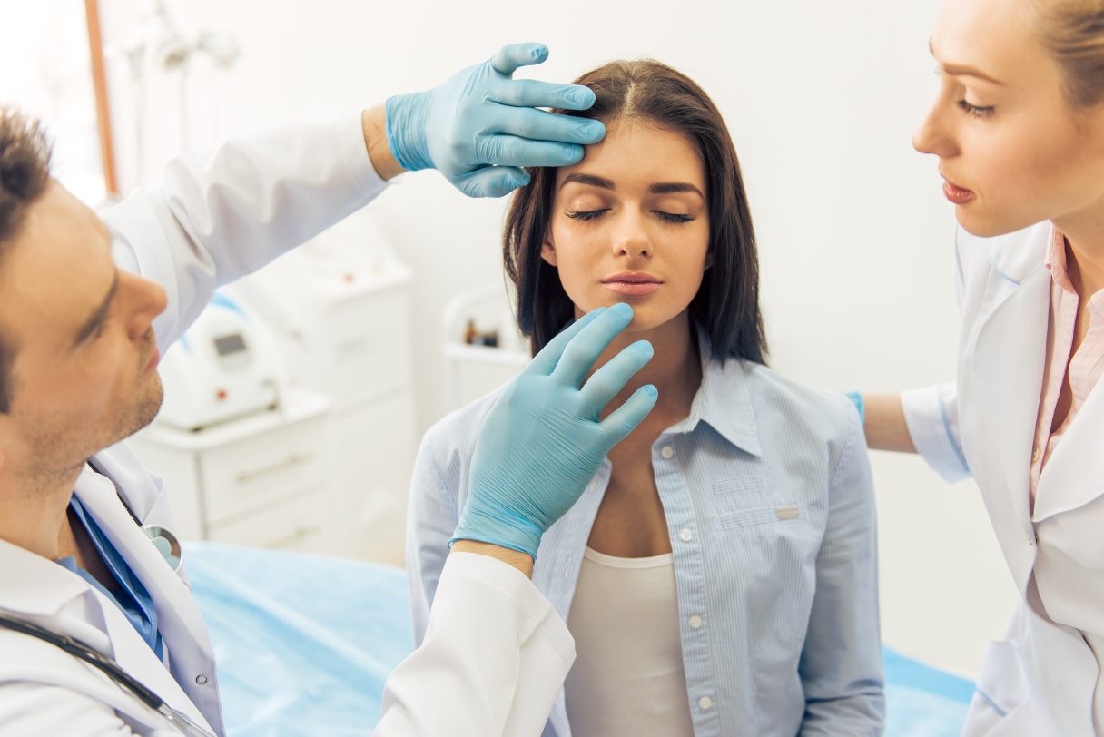 Woman having her face assessed by a plastic surgeon and assistant
