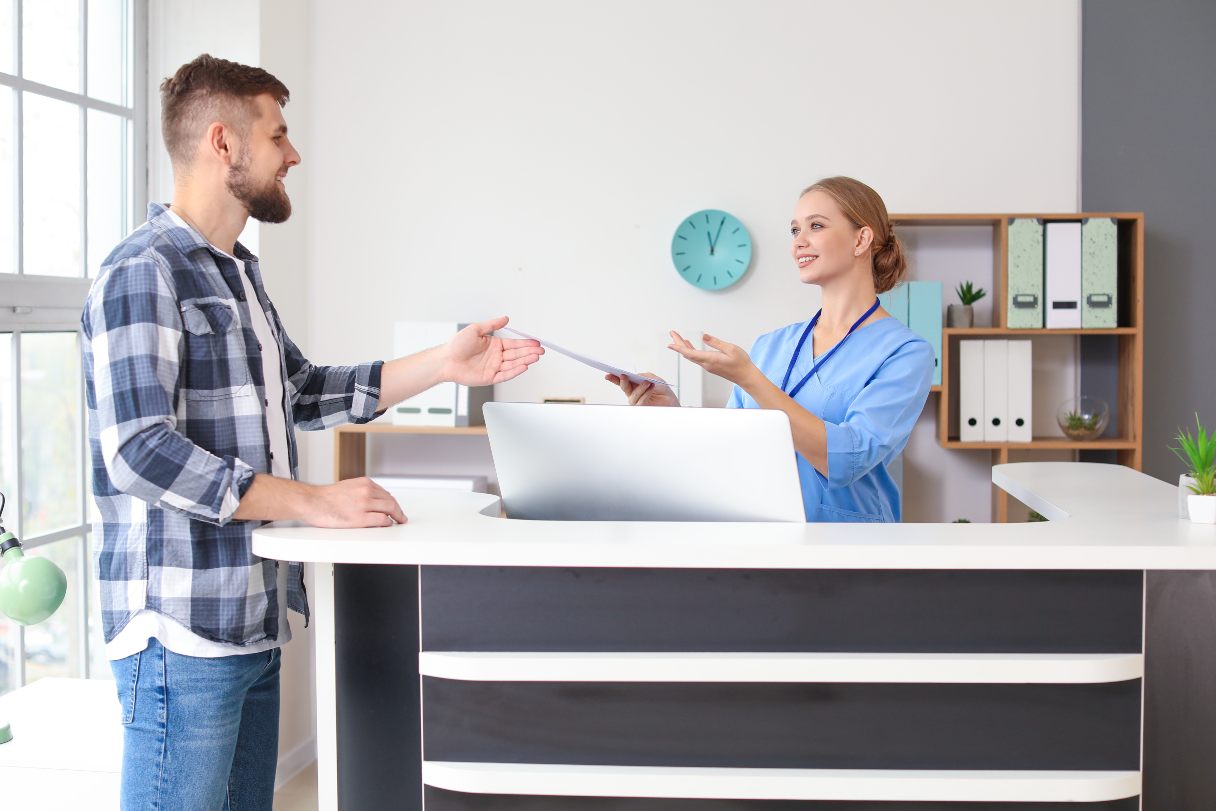 Man taking clipboard from healthcare receptionist