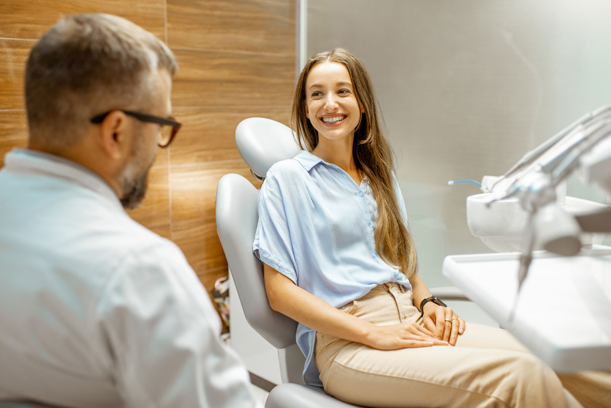 Smiling woman in dental chair, speaking with dentist