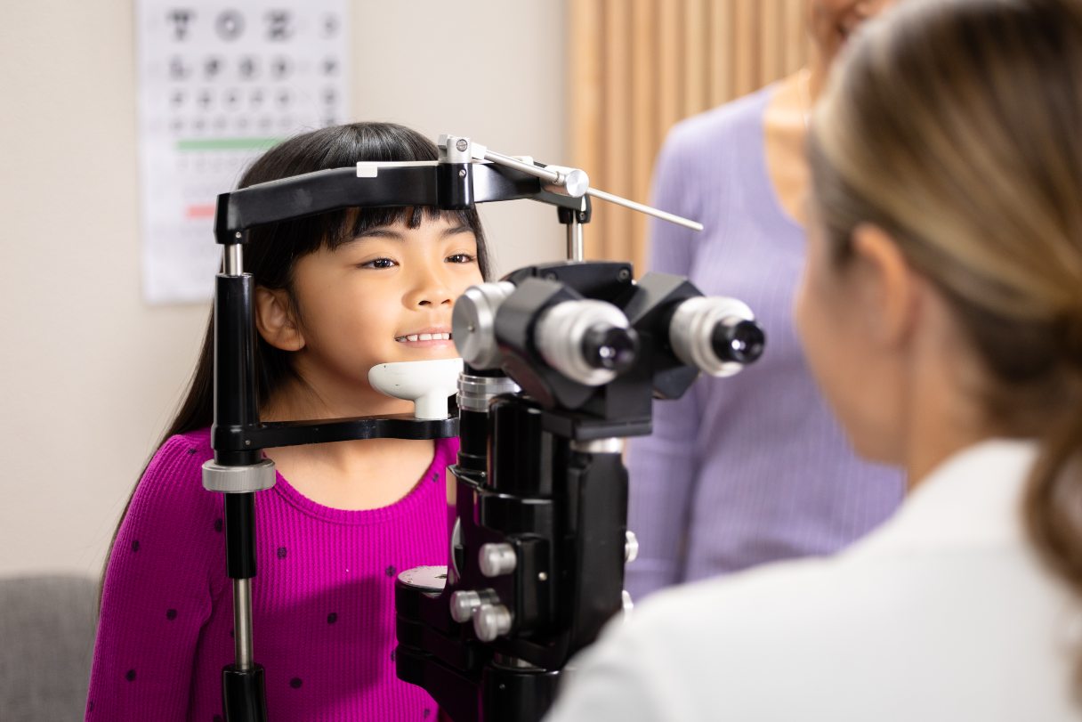 Optometrist performing exam on young girl
