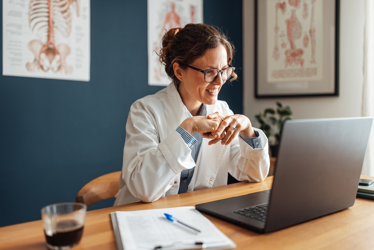 Close-up of a doctor in white coat, working at laptop