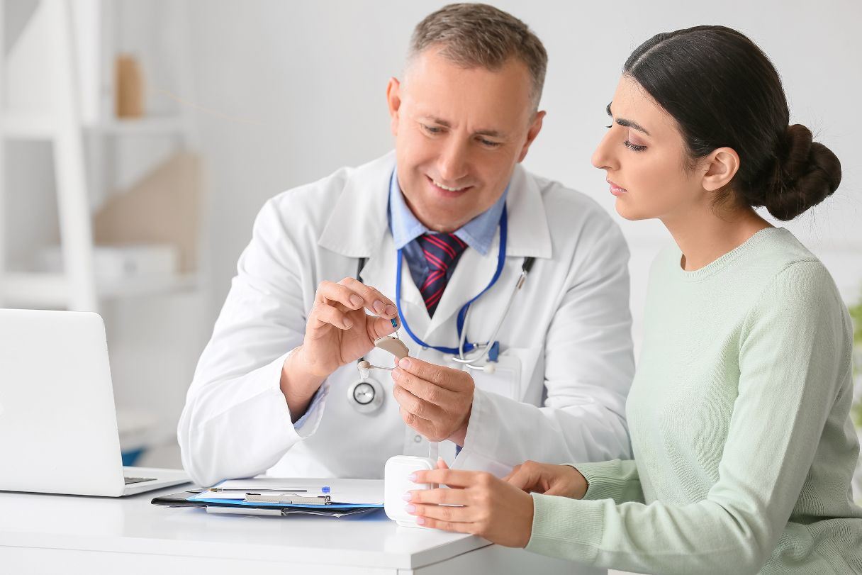 Audiologist showing patient a hearing aid