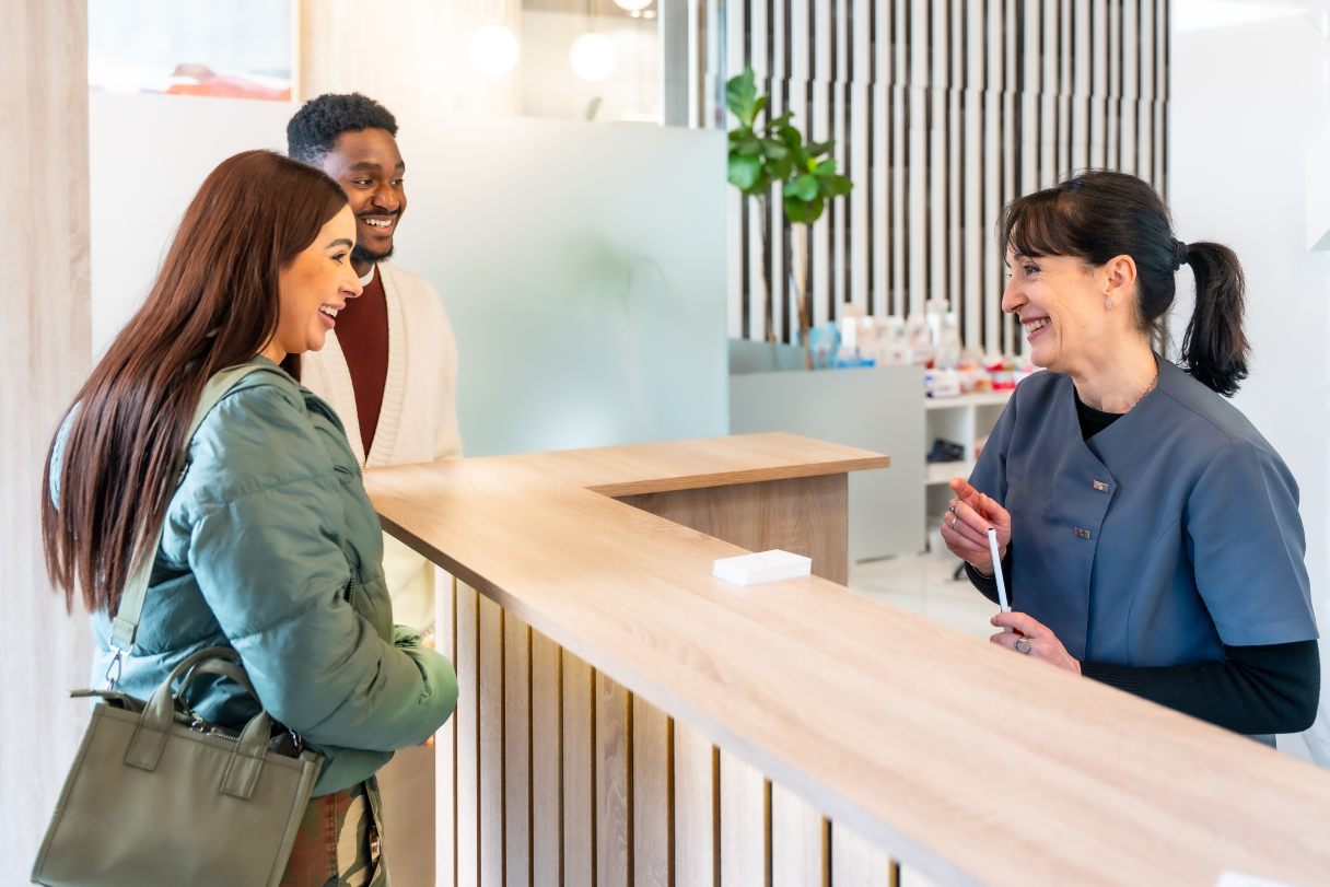 Man and woman speaking with dental receptionist
