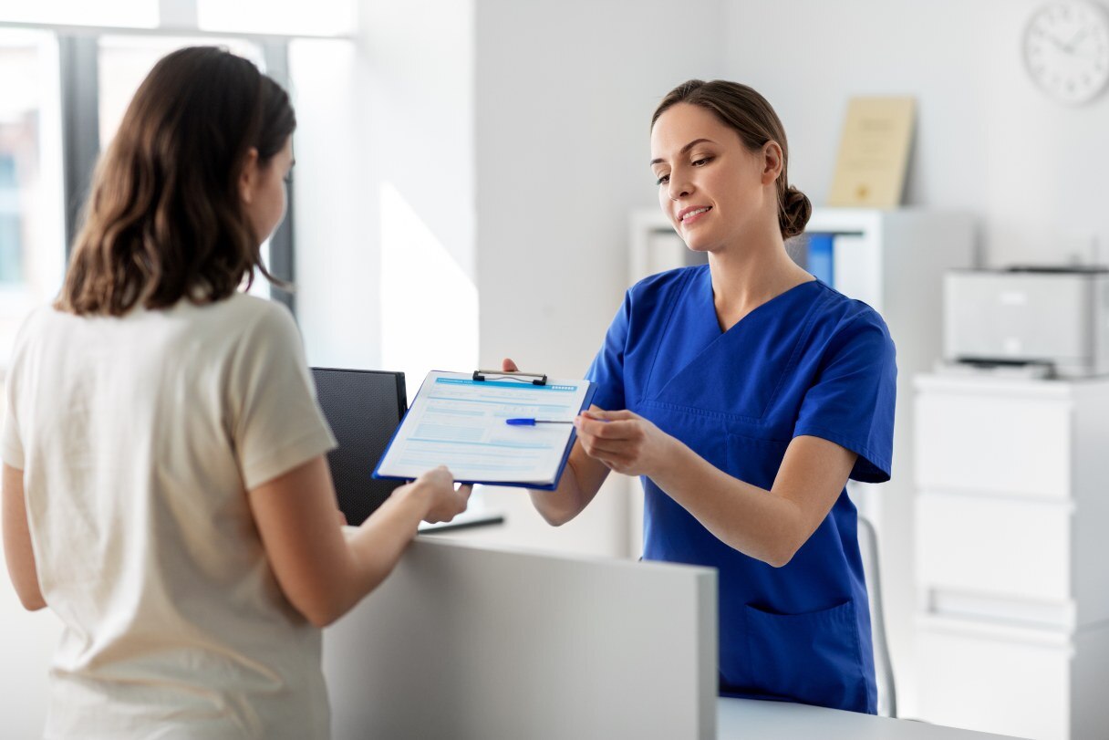 Woman passing clipboard back to healthcare receptionist
